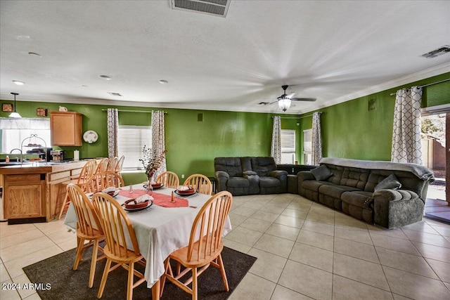 tiled dining area with ceiling fan, a wealth of natural light, crown molding, and sink