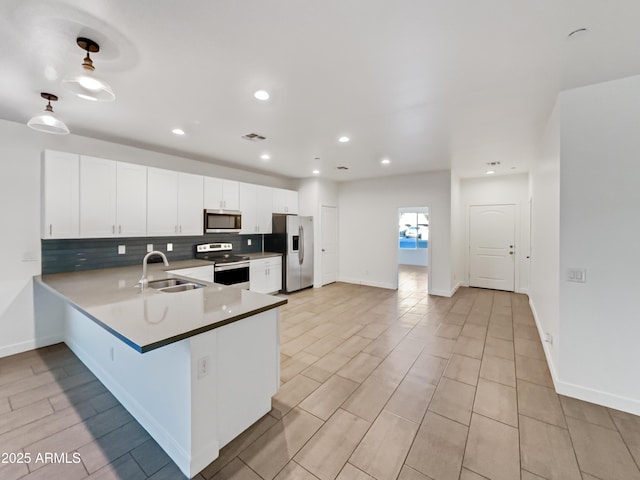 kitchen featuring white cabinetry, sink, backsplash, kitchen peninsula, and appliances with stainless steel finishes