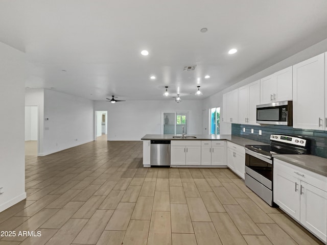 kitchen featuring kitchen peninsula, tasteful backsplash, stainless steel appliances, sink, and white cabinets