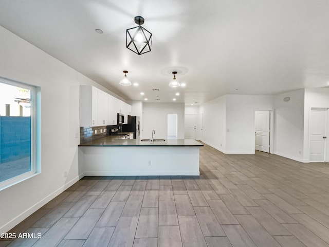 kitchen featuring pendant lighting, white cabinets, sink, appliances with stainless steel finishes, and kitchen peninsula