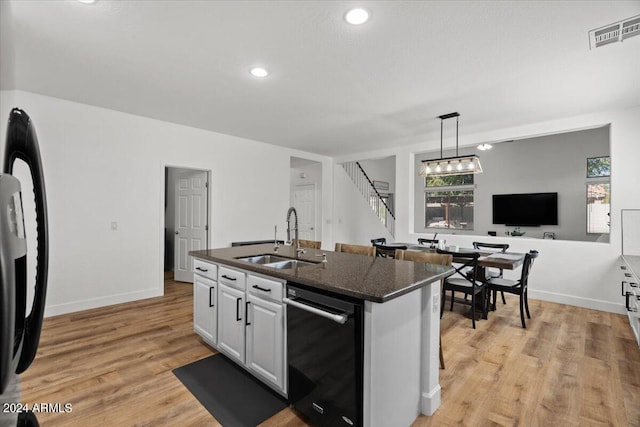 kitchen with white cabinetry, sink, light wood-type flooring, and a kitchen island with sink