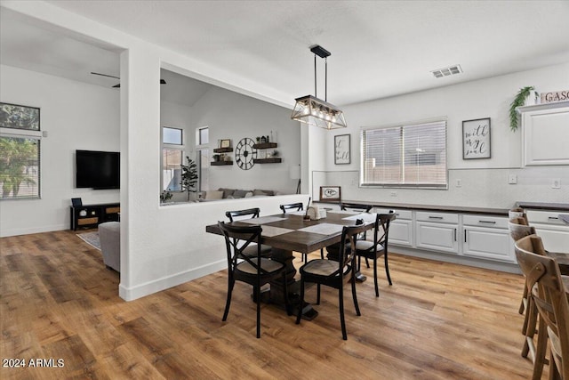 dining space with lofted ceiling, a notable chandelier, and light wood-type flooring