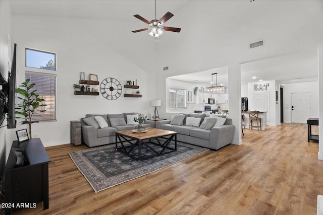 living room with hardwood / wood-style flooring, high vaulted ceiling, and ceiling fan with notable chandelier