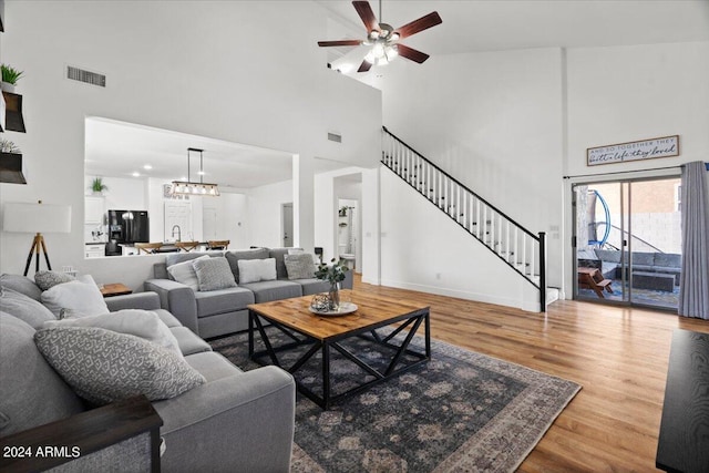 living room featuring hardwood / wood-style floors, ceiling fan with notable chandelier, and high vaulted ceiling