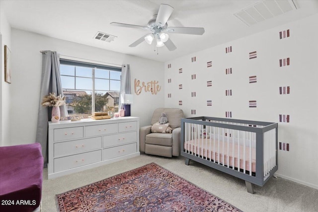 carpeted bedroom featuring a crib and ceiling fan