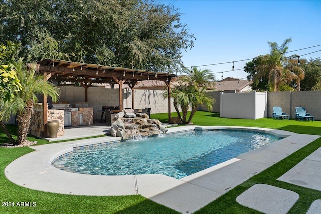 view of pool with a yard, an outdoor kitchen, a pergola, pool water feature, and a patio