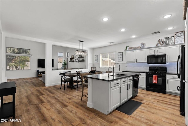 kitchen featuring white cabinets, light hardwood / wood-style flooring, black appliances, pendant lighting, and sink