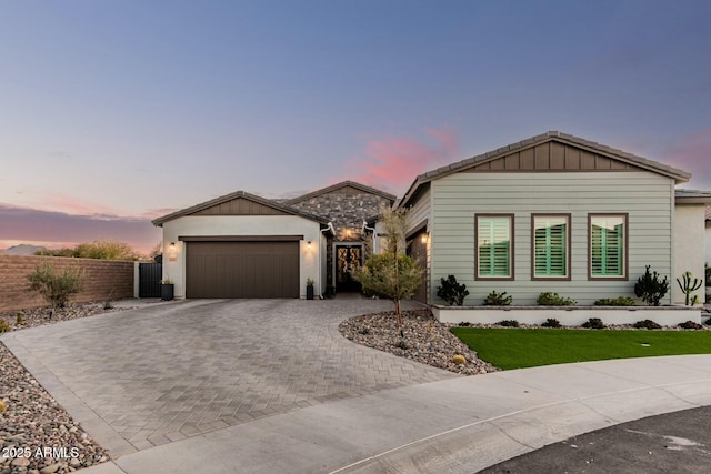 view of front facade with a garage, decorative driveway, and fence