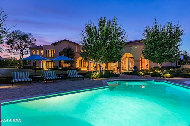 pool at dusk featuring a patio area