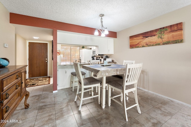 dining space with a chandelier, a textured ceiling, and light tile patterned floors