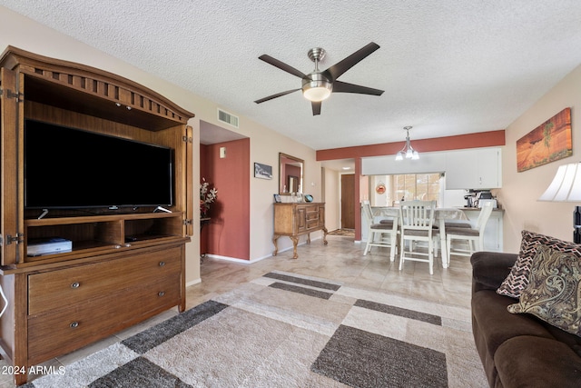 living room with a textured ceiling, ceiling fan with notable chandelier, and light tile patterned flooring