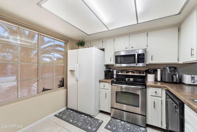 kitchen with white cabinets, appliances with stainless steel finishes, and light tile patterned floors