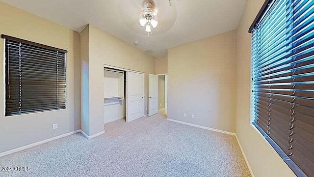 unfurnished bedroom featuring lofted ceiling, light carpet, a closet, and ceiling fan