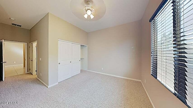 unfurnished bedroom featuring lofted ceiling, light colored carpet, a closet, and ceiling fan