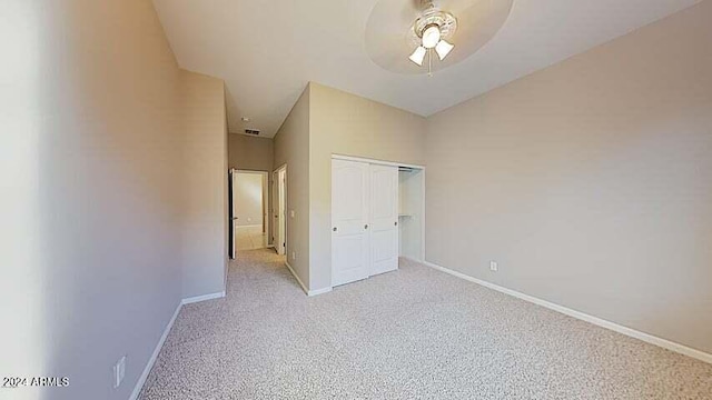 unfurnished bedroom with light colored carpet, a closet, and ceiling fan