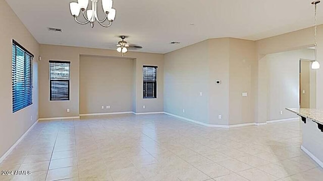 empty room with ceiling fan with notable chandelier and light tile patterned floors