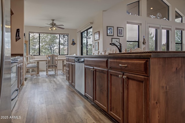 kitchen featuring light wood-style floors, a ceiling fan, vaulted ceiling, and stainless steel dishwasher