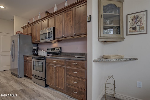 kitchen with dark countertops, stainless steel appliances, and light wood-type flooring