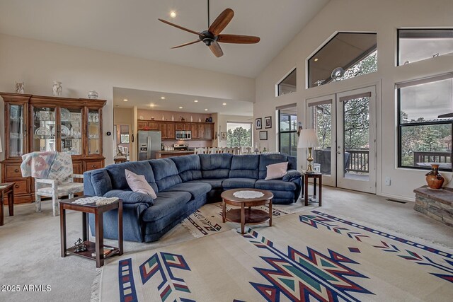 living room featuring plenty of natural light, visible vents, high vaulted ceiling, and light colored carpet