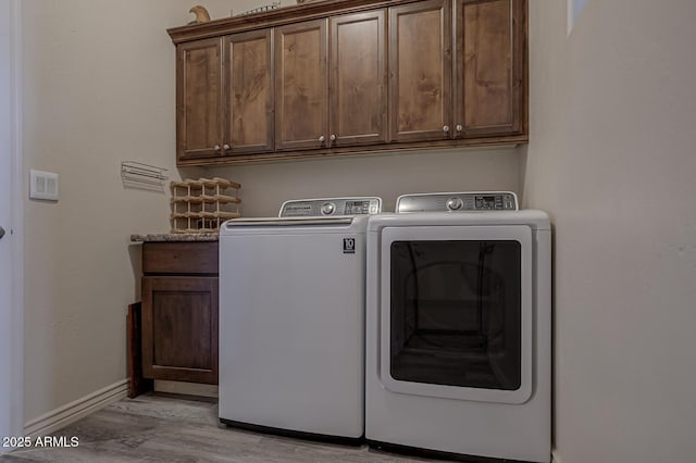 washroom featuring washer and dryer, cabinet space, light wood-style flooring, and baseboards