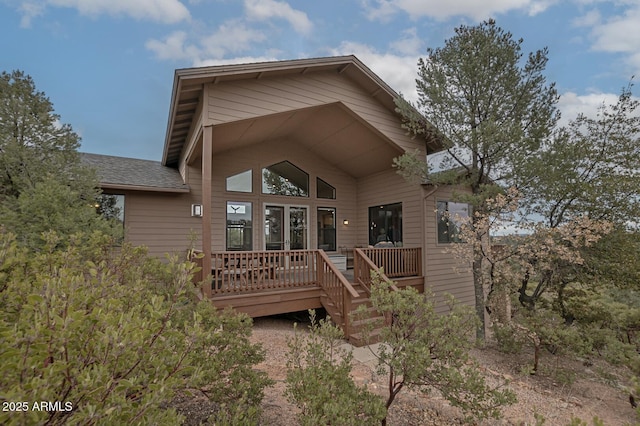 rear view of property with roof with shingles and a deck