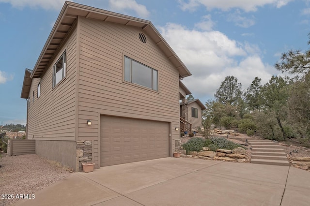 view of side of home featuring an attached garage and concrete driveway