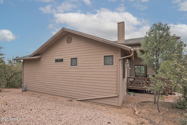 view of side of property featuring a chimney and a wooden deck