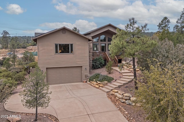 view of front of house with driveway, an attached garage, and stairs