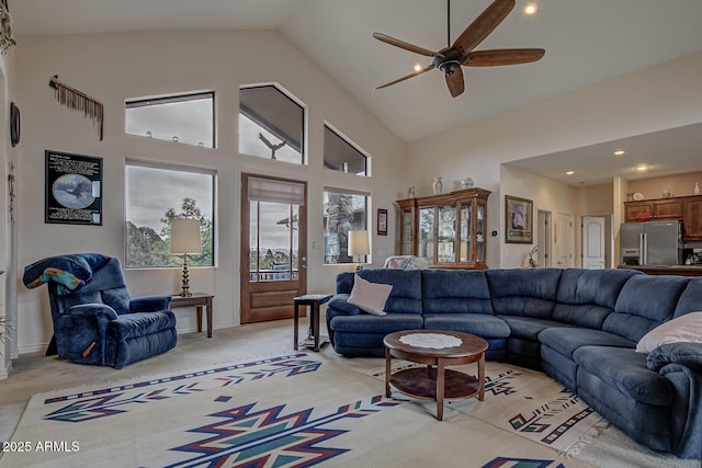 living area with high vaulted ceiling, a ceiling fan, and light colored carpet