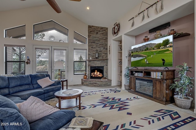 carpeted living room featuring high vaulted ceiling, a stone fireplace, built in shelves, a ceiling fan, and beam ceiling