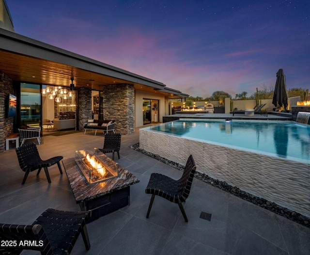 pool at dusk with a patio area, an outdoor pool, a fire pit, and ceiling fan