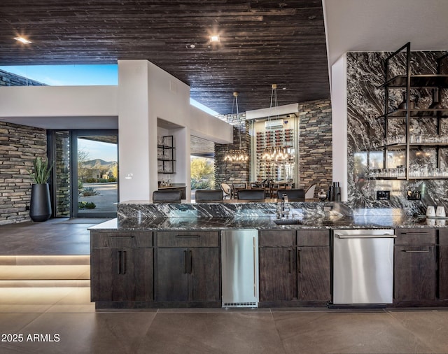 bar featuring indoor wet bar, a towering ceiling, and concrete floors