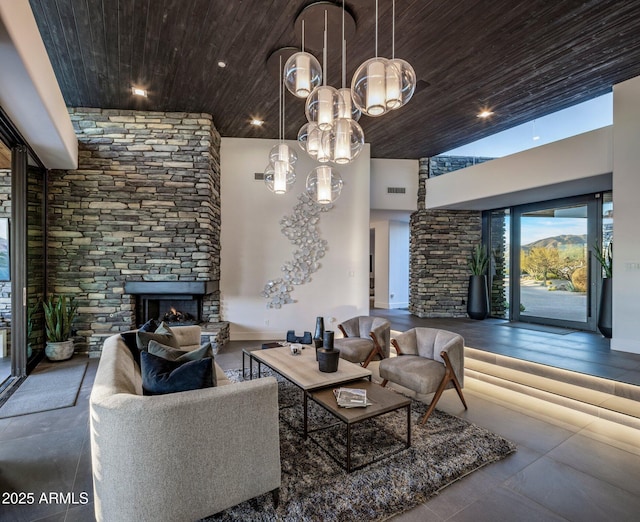 living room with a stone fireplace, an inviting chandelier, wooden ceiling, and visible vents