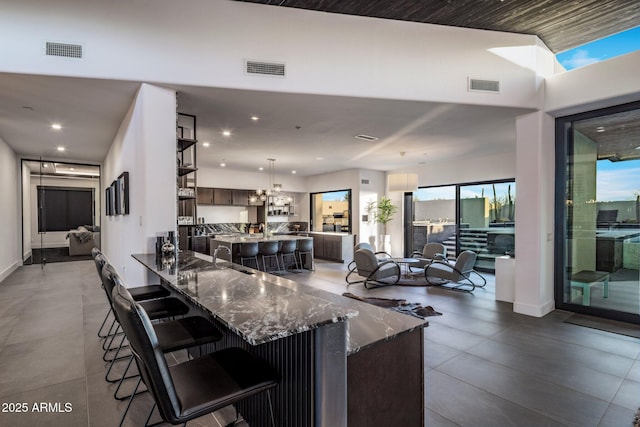 kitchen featuring dark stone countertops, a kitchen breakfast bar, visible vents, and dark brown cabinetry