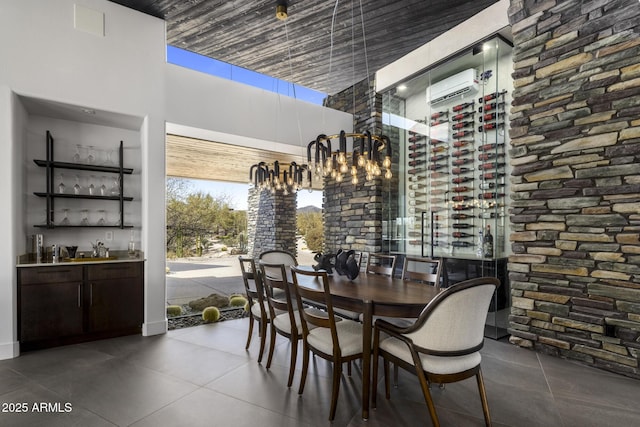 tiled dining room featuring indoor wet bar, a notable chandelier, a high ceiling, and a wall unit AC