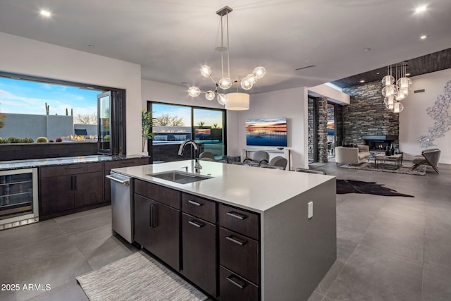 kitchen with beverage cooler, an inviting chandelier, a kitchen island with sink, a sink, and open floor plan