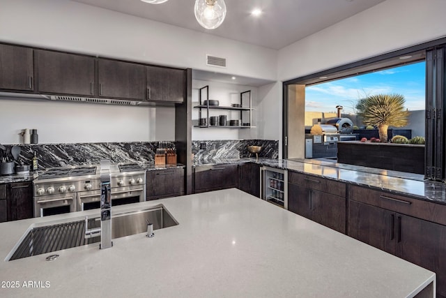 kitchen featuring beverage cooler, dark brown cabinets, double oven range, and visible vents