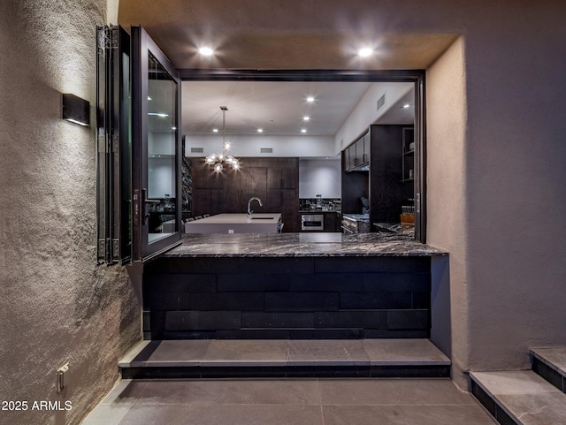 kitchen featuring modern cabinets, recessed lighting, a textured wall, and a sink