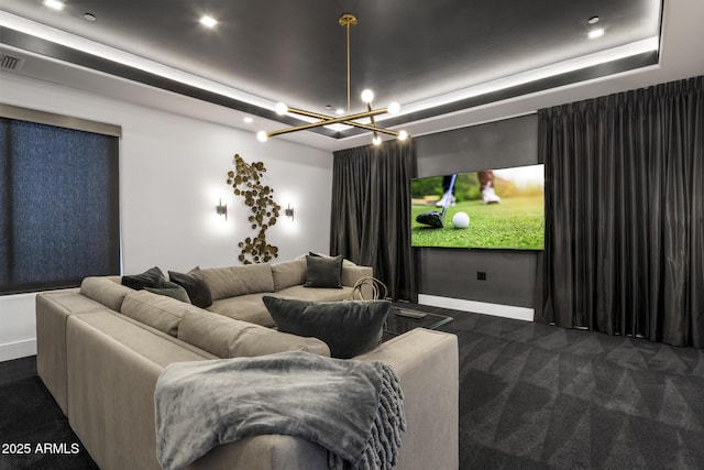 carpeted cinema room featuring visible vents, an inviting chandelier, baseboards, and a tray ceiling