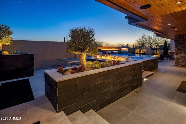 patio terrace at dusk featuring an outdoor pool and an outdoor fire pit