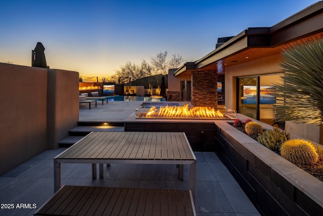 patio terrace at dusk with an outdoor pool and an outdoor fire pit