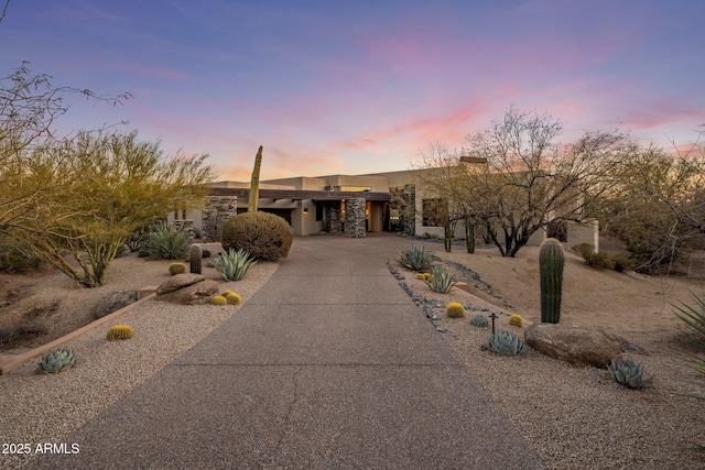 pueblo-style house with stucco siding, driveway, and a garage