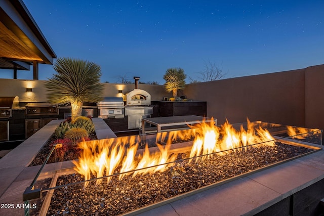 view of patio with a grill, an outdoor fire pit, and exterior kitchen