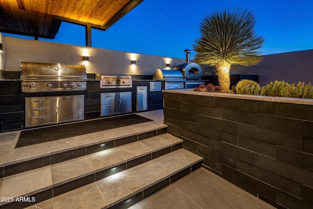 patio at twilight featuring area for grilling and a grill