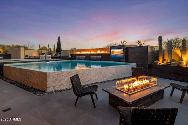 outdoor pool featuring an outdoor fire pit and a patio