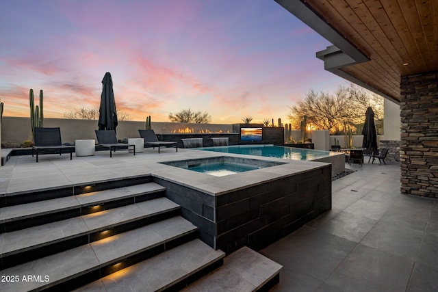 view of pool with a fire pit, an in ground hot tub, a fenced backyard, and a patio