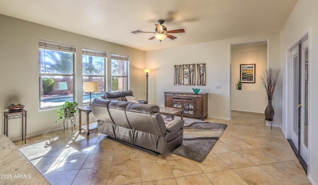 living room with a ceiling fan, visible vents, baseboards, and light tile patterned floors