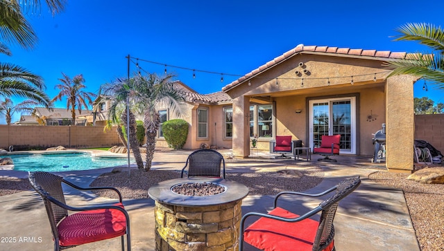 view of patio with a fenced in pool, fence, and a fire pit