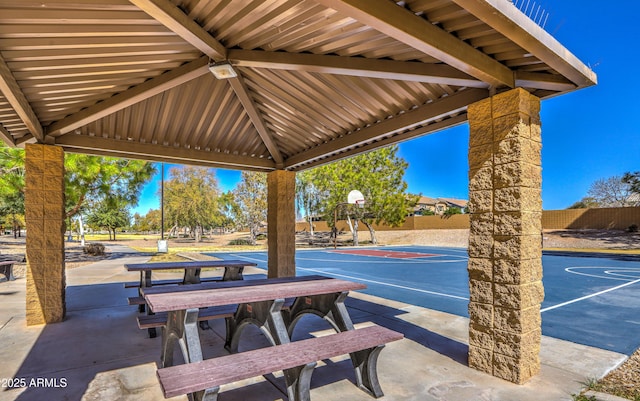 view of patio with community basketball court and fence