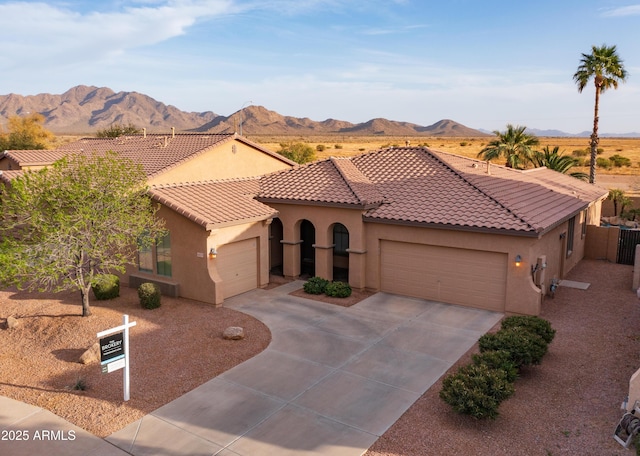 mediterranean / spanish home with driveway, a tile roof, an attached garage, a mountain view, and stucco siding